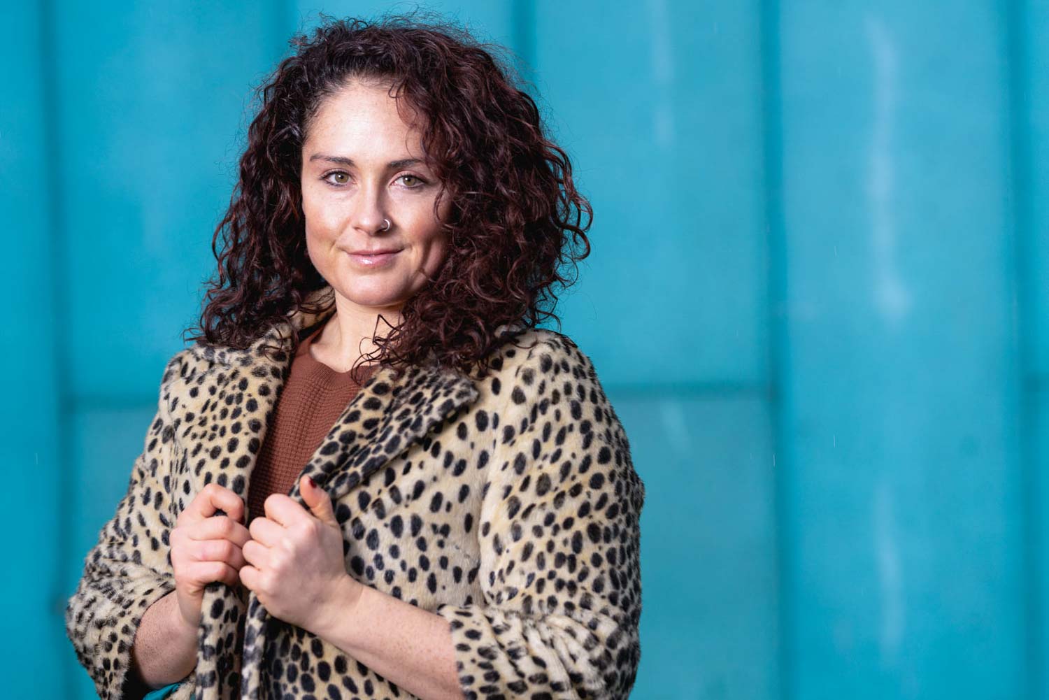 Portrait of a woman in a leopard print coat against a turquoise wall, Newport portrait photography