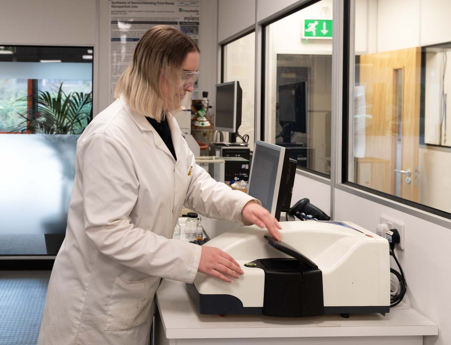 Scientist in a white lab coat operating a spectrometer in a research laboratory