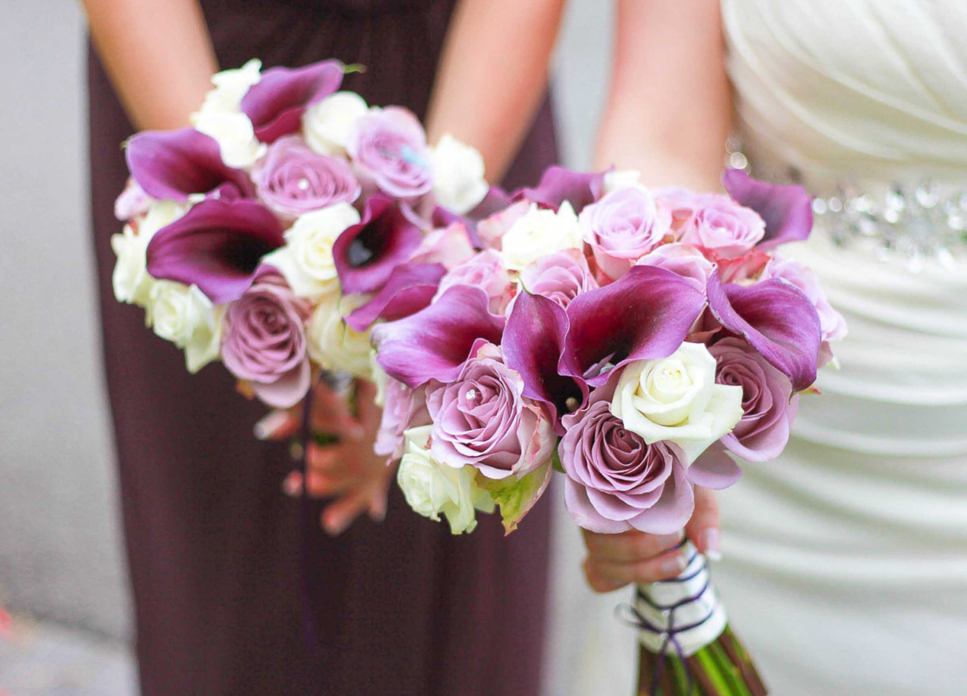 Bride and bridesmaid holding purple calla lily and rose bouquets