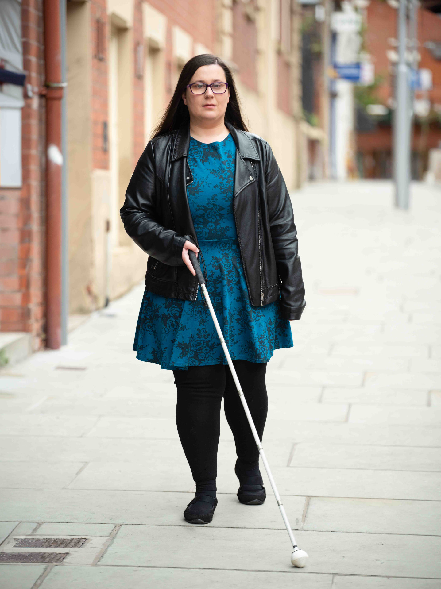 Woman walking a city street with a white cane, photographed for a charity campaign in Wales