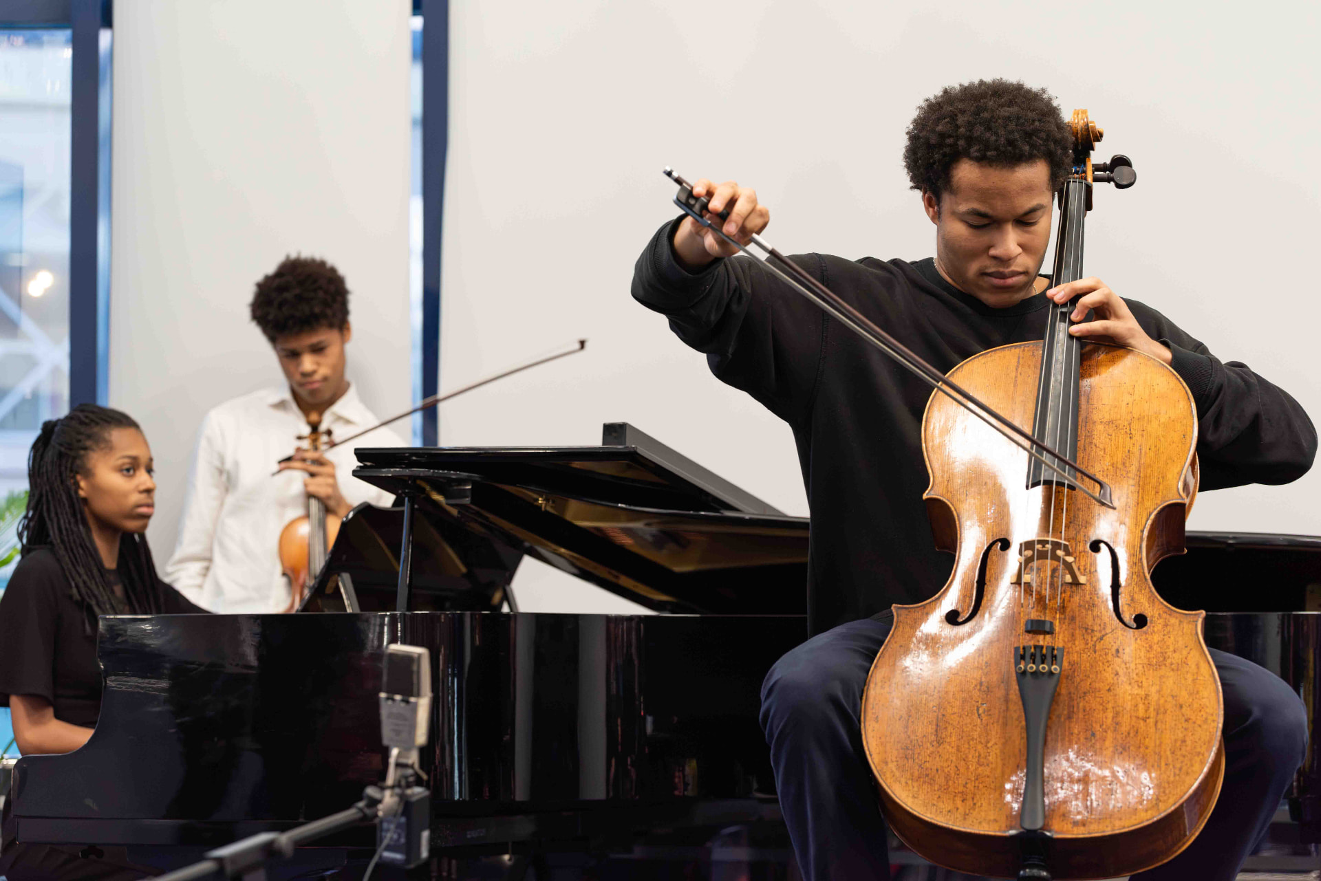 Cellist performing with a pianist and violinist at a commercial publicity event in South Wales