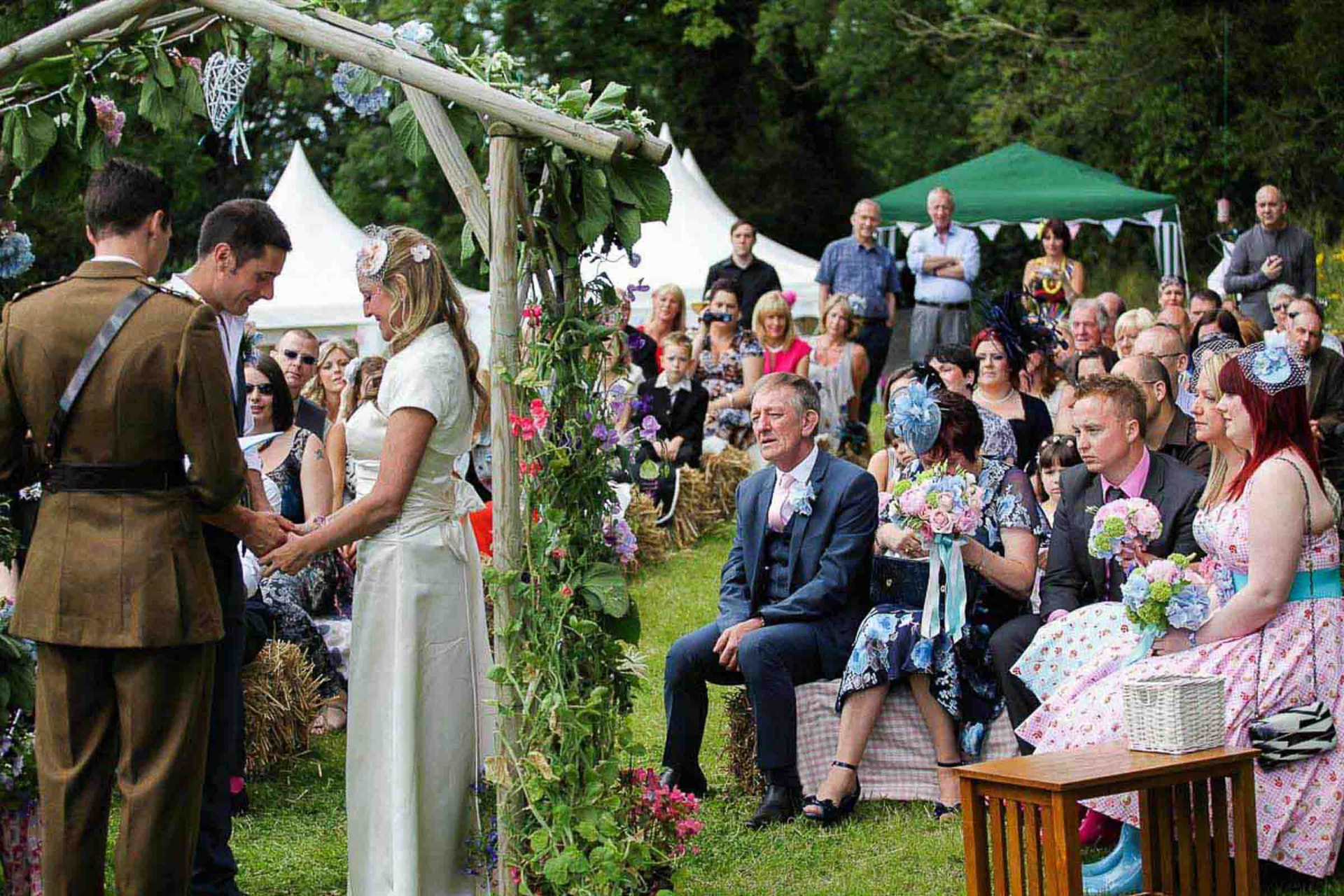 Outdoor garden wedding ceremony near Cardiff with guests watching the ring exchange